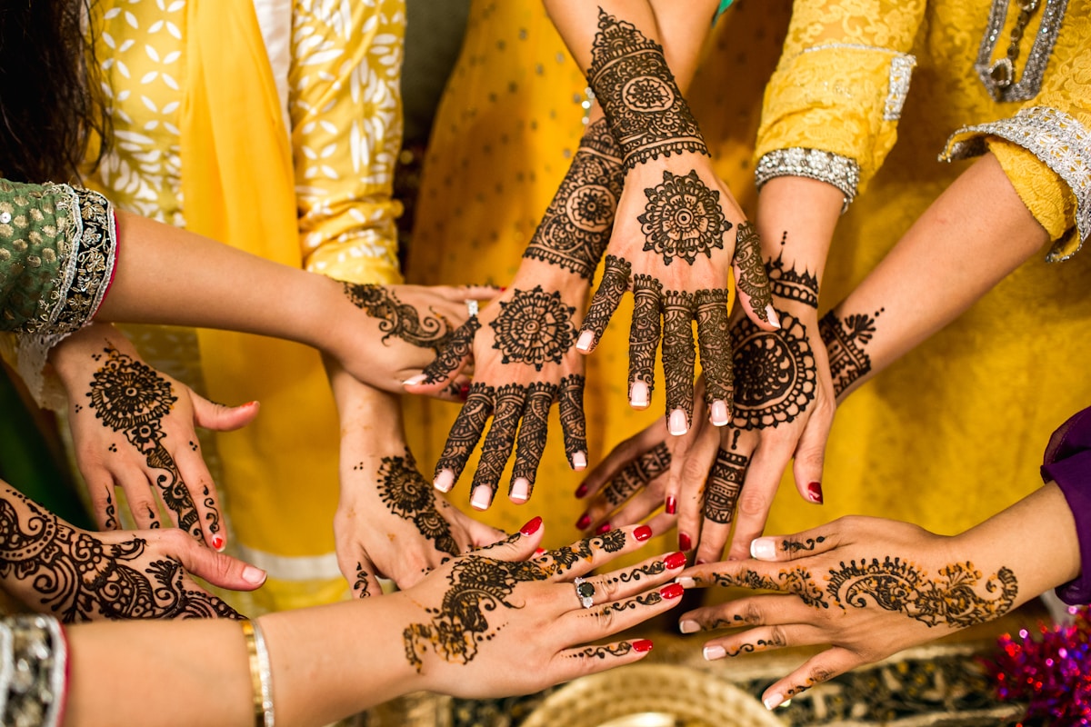 Intricate henna designs on hands over yellow wedding attire