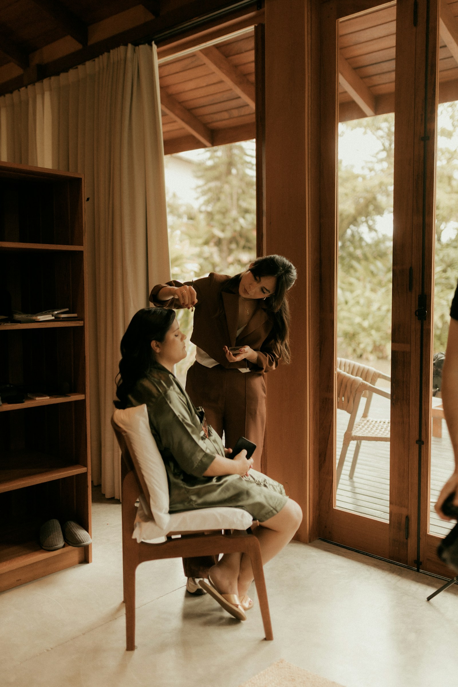 Makeup artist preparing a client beside a sunlit window